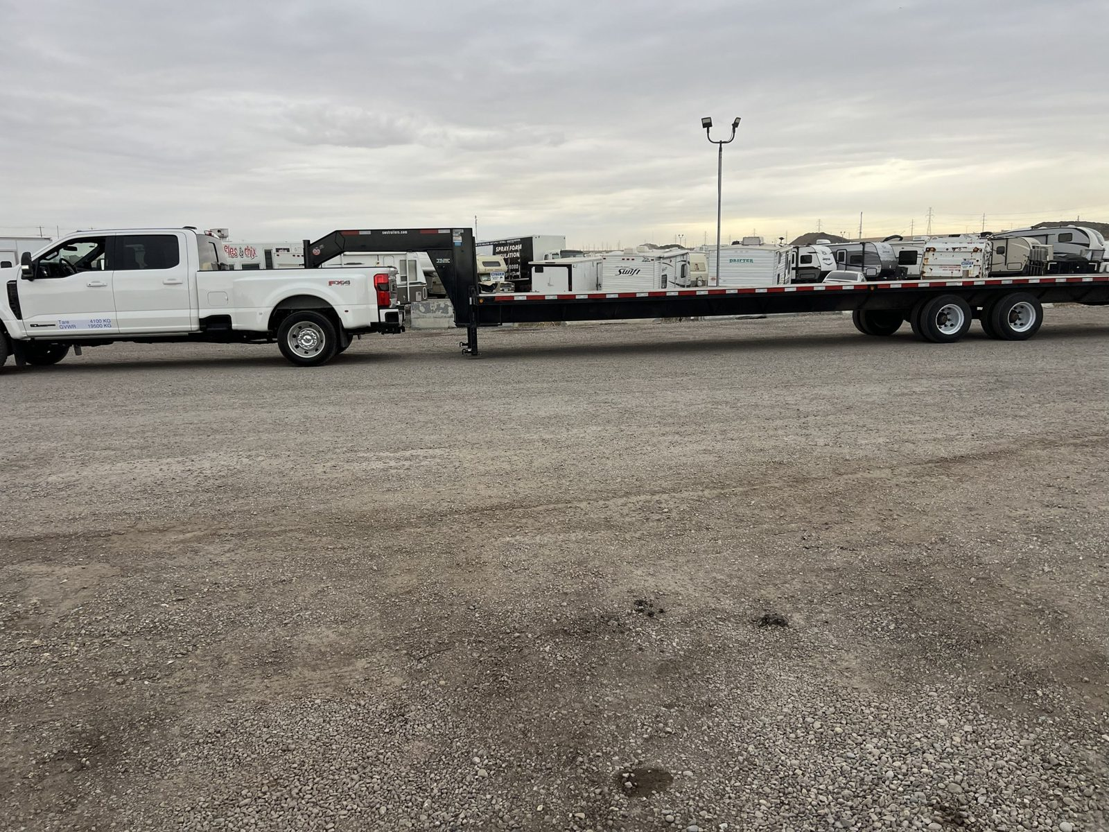 Gooseneck flatbed trailer behind a white Ford dually