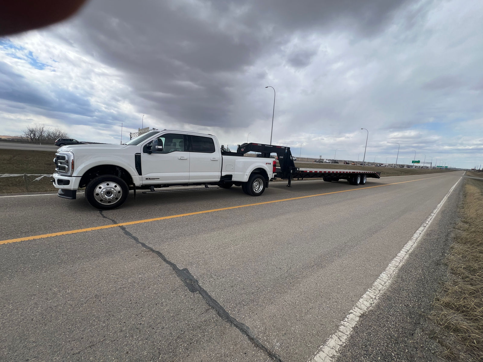 Logistics Service World truck and gooseneck flatbed trailer on an Alberta highway